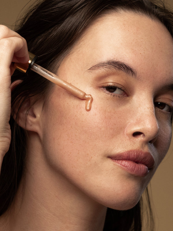 Model applying Antipodes Credo Probiotic Anti-Blemish Serum with a dropper