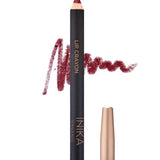 A crimson INIKA Organic Lip Crayons 6.7g with a color swatch behind it, labeled LIP CRAYON and INIKA ORGANIC. A gold cap sits beside it, while "Crimson" below highlights this long-lasting organic lip liner.
