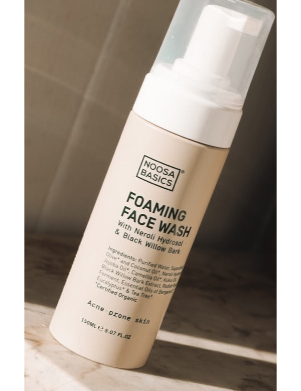 Noosa Basics Foaming Face Wash for acne-prone skin on a sunlit stone surface.