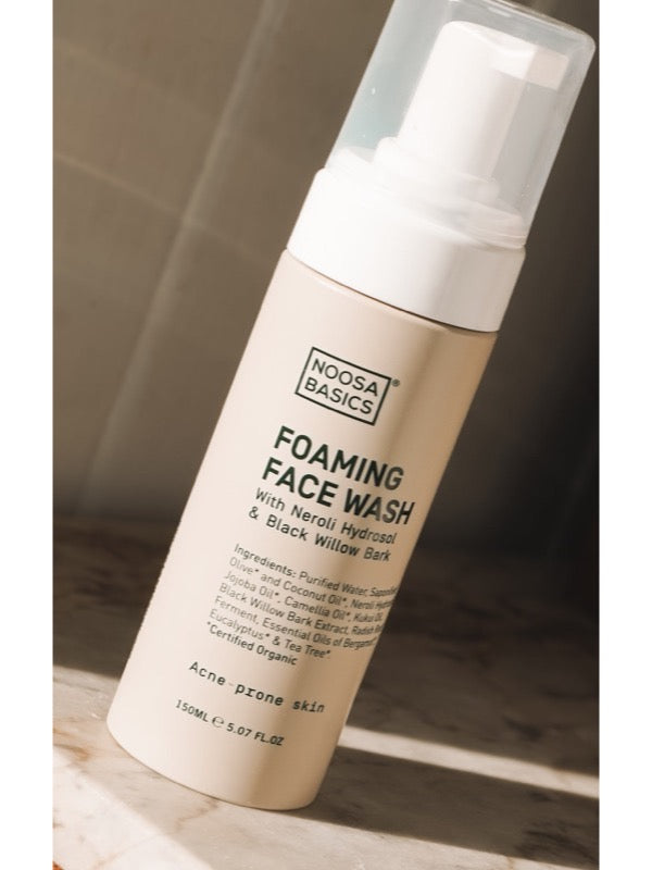 Noosa Basics Foaming Face Wash for acne-prone skin on a sunlit stone surface.