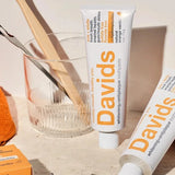 Davids Orange and Vanilla Toothpaste displayed with a toothbrush and glass