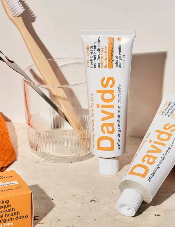 Davids Orange and Vanilla Toothpaste displayed with a toothbrush and glass