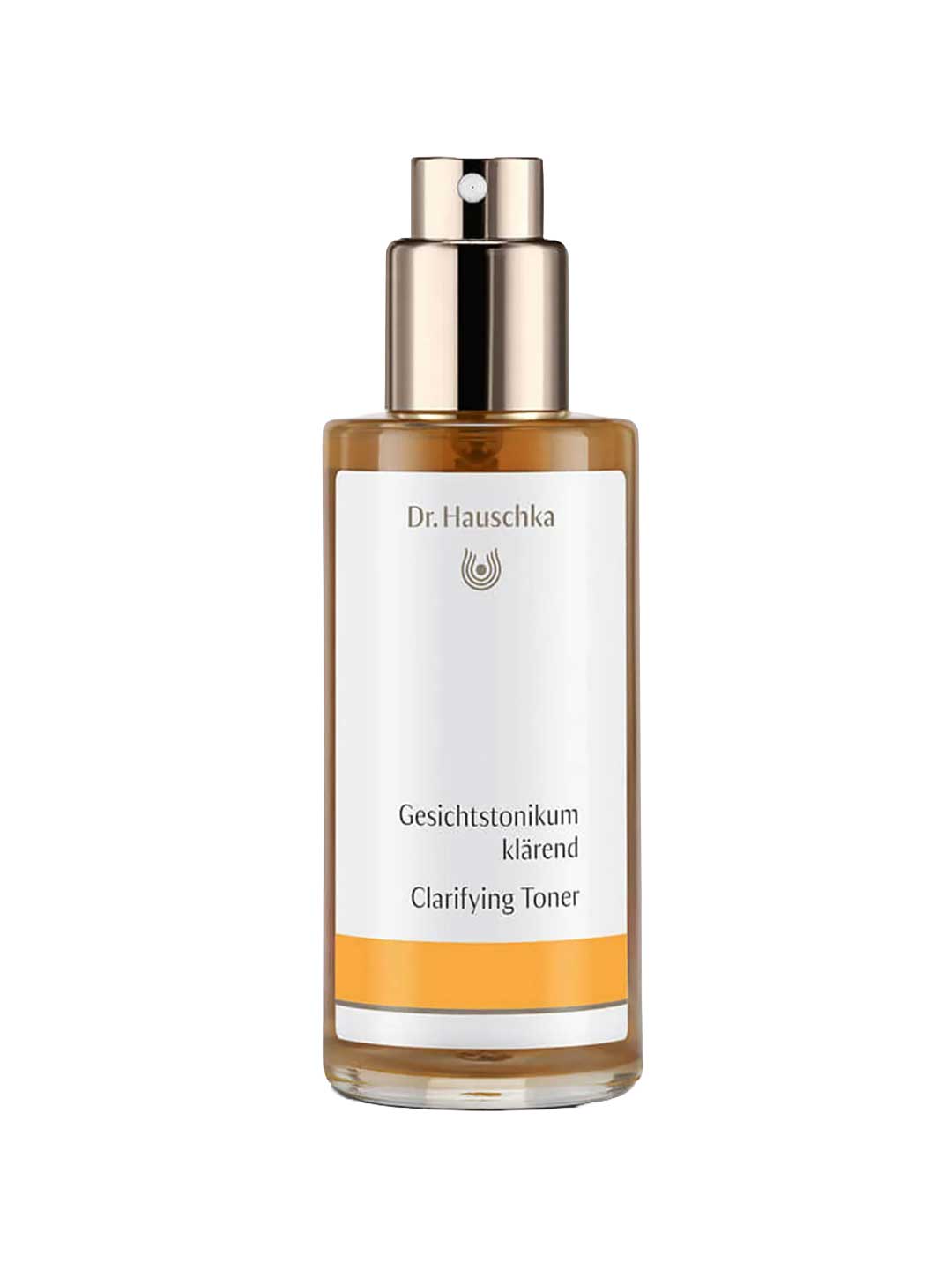 Dr Hauschka Clarifying Toner 100ml comes in a clear bottle with a gold spray pump and amber liquid inside. The white label features orange accents and text in German and English. Ideal for oily or blemished skin.