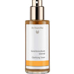Dr Hauschka Clarifying Toner 100ml comes in a clear bottle with a gold spray pump and amber liquid inside. The white label features orange accents and text in German and English. Ideal for oily or blemished skin.