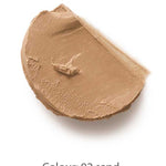 A swipe of Dr Hauschka Coverstick 2g in shade 02 sand is displayed on a white background, highlighting its creamy beige formula ideal for naturally concealing blemishes.