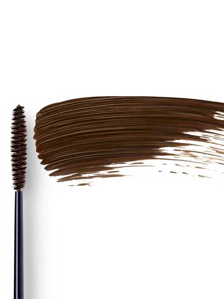 Dr Hauschka Defining Mascara 6ml is shown with a black wand coated in brown product next to a large brown swipe, ideal for sensitive eyes, all set against a white background.