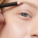 A close-up shows a person with fair skin applying Dr Hauschka Eyebrow Definer 1.05g to their eyebrow. The pencil is held above the brow. Text below reads: Colour: 01 light brown.