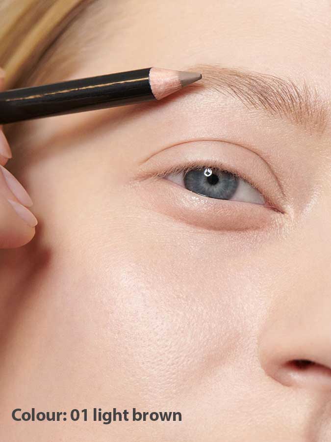 A close-up shows a person with fair skin applying Dr Hauschka Eyebrow Definer 1.05g to their eyebrow. The pencil is held above the brow. Text below reads: Colour: 01 light brown.
