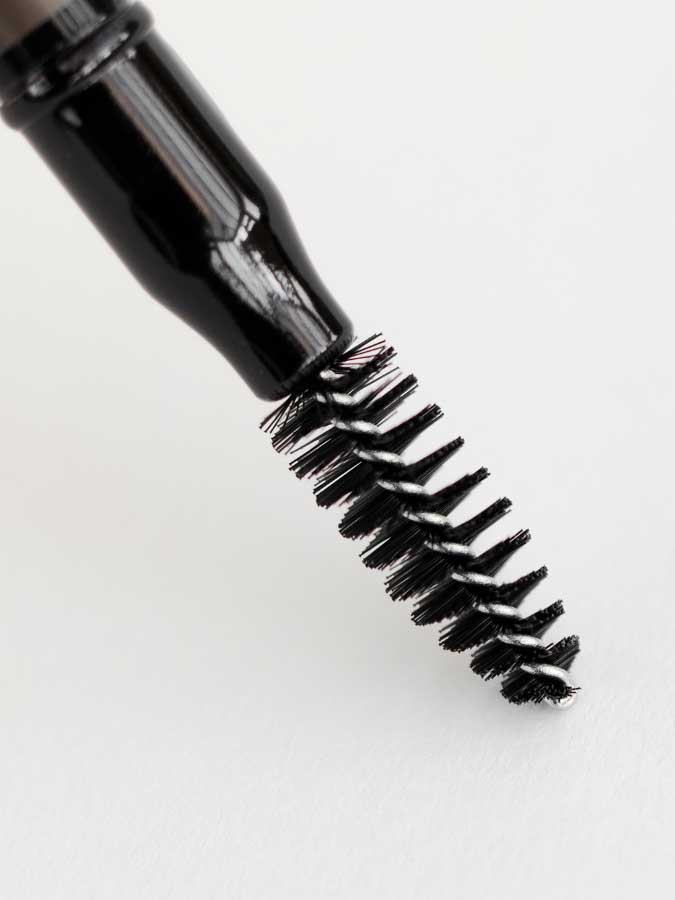 A close-up of a black mascara wand with bristled brush, shown against a white background—perfectly complementing the Dr Hauschka Eyebrow Definer 1.05g for a polished, natural look.