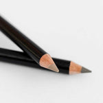 Two black wooden Dr Hauschka Eyebrow Definer pencils (1.05g), both sharpened, are placed on a white surface, with one pencil crossing over the other.