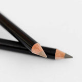 Two black wooden Dr Hauschka Eyebrow Definer pencils (1.05g), both sharpened, are placed on a white surface, with one pencil crossing over the other.