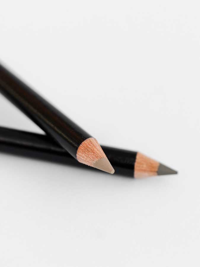 Two black wooden Dr Hauschka Eyebrow Definer pencils (1.05g), both sharpened, are placed on a white surface, with one pencil crossing over the other.