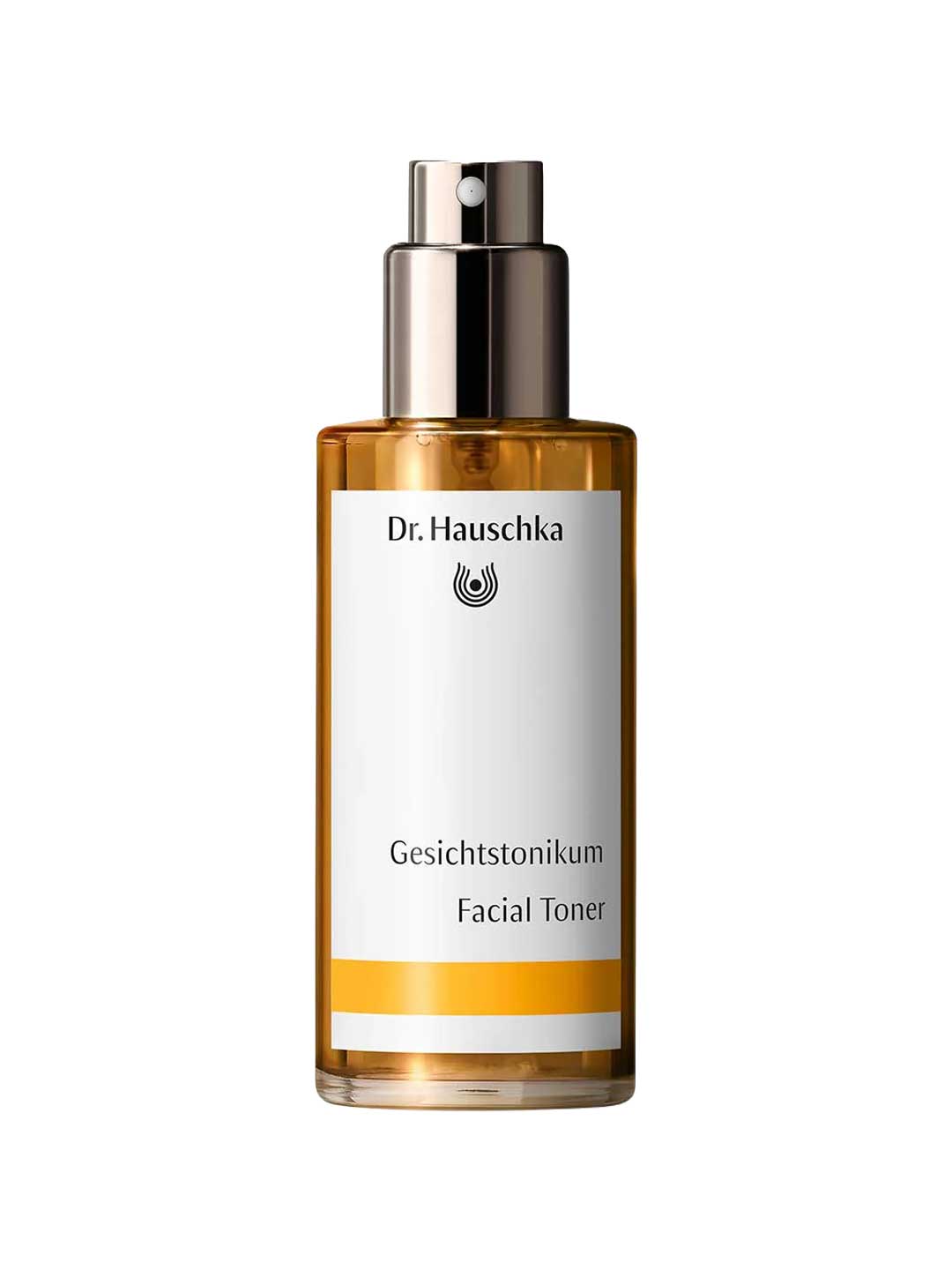 Dr Hauschka Facial Toner 100ml features a gold spray cap and a white label with black German and English text. Presented on a plain white background, it's ideal for sensitive skin with its soothing Witch Hazel formula.