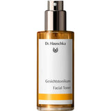 Dr Hauschka Facial Toner 100ml features a gold spray cap and a white label with black German and English text. Presented on a plain white background, it's ideal for sensitive skin with its soothing Witch Hazel formula.