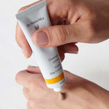 A person squeezes a small amount of Dr Hauschka Tinted Day Cream 30ml onto the back of their hand for a natural, radiant glow.