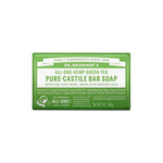 A 140g green and white Dr. Bronner's Pure-Castile Bar Soap in Green Tea, with product info, organic ingredients, and certifications displayed on the front label.