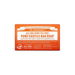 A 140g rectangular bar of Dr. Bronner's Pure-Castile Bar Soap in tea tree scent features an orange and white label with fair trade and organic details, plus product and brand information.