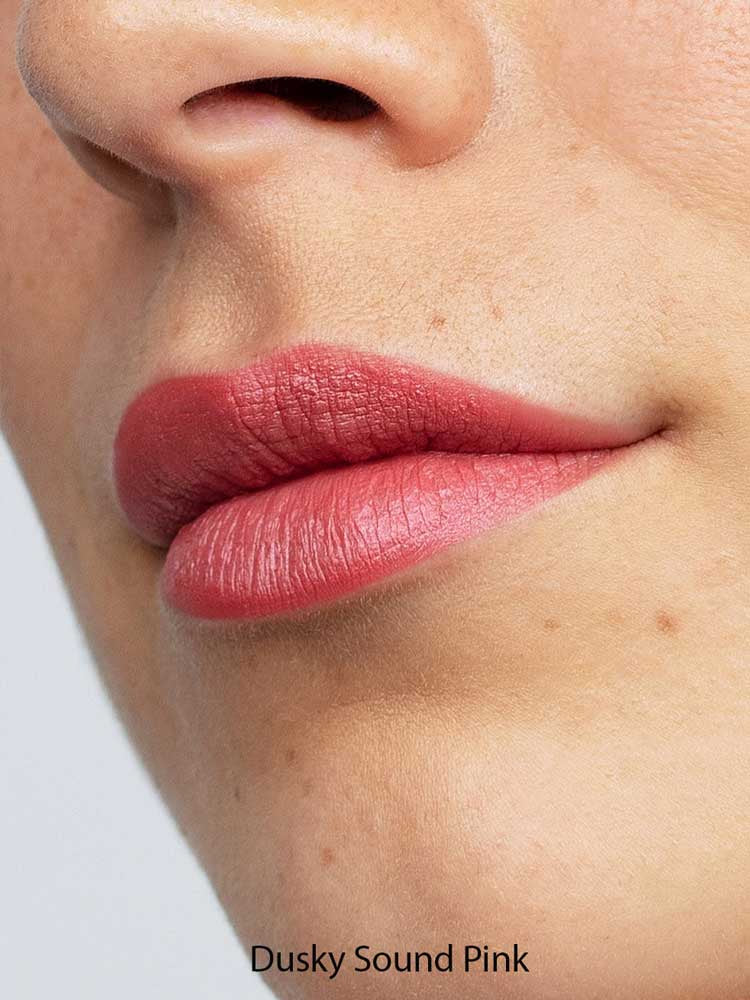 A close-up of lips wearing Antipodes Moisture Boost Natural Lipsticks 4g in matte dusky pink, with smooth skin visible. Infused with Avocado Oil for hydration. The text "Dusky Sound Pink" appears at the bottom of the image.
