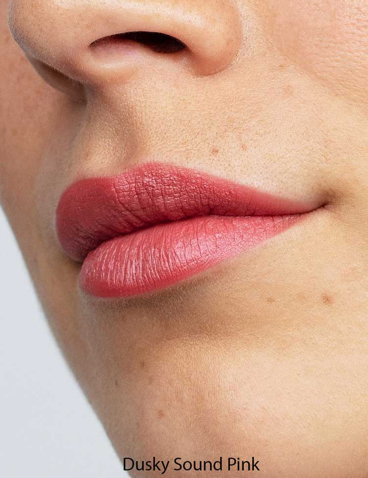 A close-up of lips wearing Antipodes Moisture Boost Natural Lipsticks 4g in matte dusky pink, with smooth skin visible. Infused with Avocado Oil for hydration. The text "Dusky Sound Pink" appears at the bottom of the image.