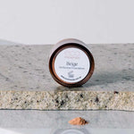 A small round container of Eco Minerals Perfection Dewy Mineral Foundation 5g sits on granite, with some loose powder spilled in front against a plain, neutral background.