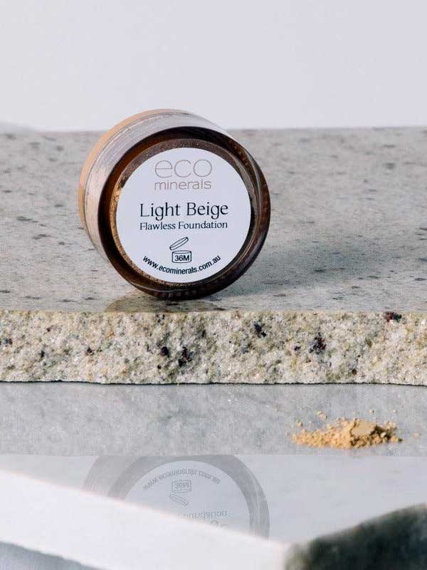 A 5g jar of Eco Minerals Flawless Matte Mineral Foundation sits on granite, with natural SPF25 and a touch of beige powder spilled nearby.