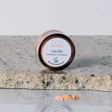 A small round container of Eco Minerals Perfection Dewy Mineral Foundation 5g rests on a granite surface, with some loose powder foundation spilled in front.