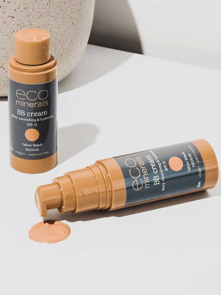 Two bottles of Eco Minerals Mineral BB Cream 32ml are shown—one upright, one lying with its cap off and dispensing light beige cream onto a white surface. Both display the “eco minerals BB cream, SPF 12” label.