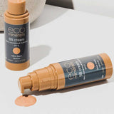 Two bottles of Eco Minerals Mineral BB Cream 32ml are shown—one upright, one lying with its cap off and dispensing light beige cream onto a white surface. Both display the “eco minerals BB cream, SPF 12” label.