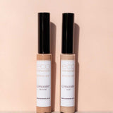 Two tubes of Eco Minerals Mineral Concealer 5g, one in Medium and one in Light, stand upright on a soft peach background with their black caps casting shadows.