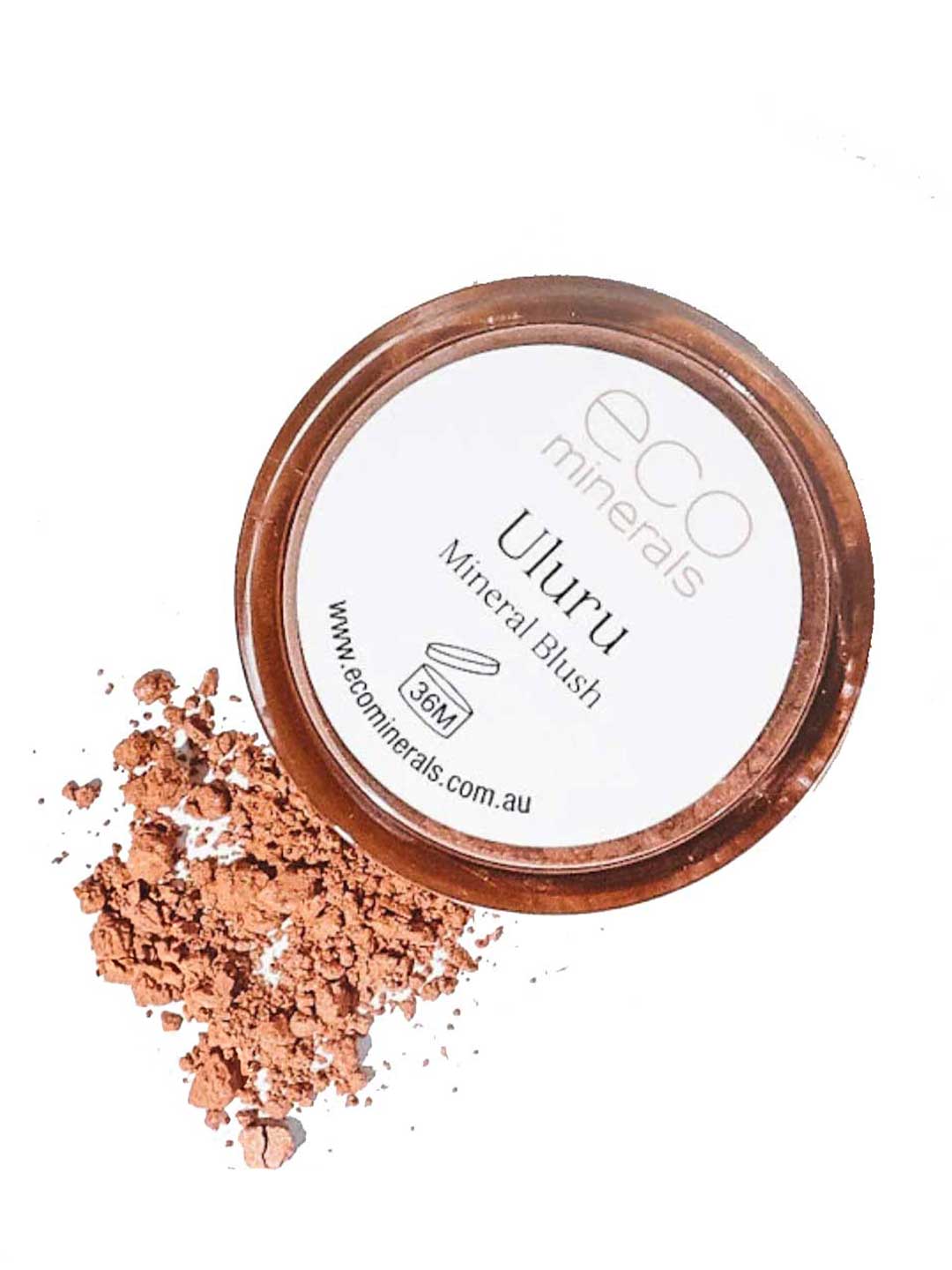 A circular container of Eco Minerals Mineral Blush - Uluru 4g sits with loose, peachy-pink vegan blush powder beside it. The lid features the brand and product name.