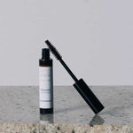 An open tube of Eco Minerals Natural Mascara 8g with a black wand sits on a granite countertop against a plain, light background.