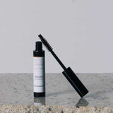 An open tube of Eco Minerals Natural Mascara 8g with a black wand sits on a granite countertop against a plain, light background.