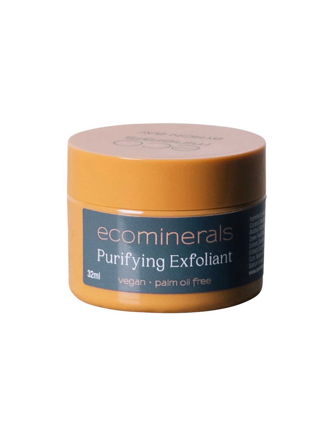 A small, round yellow container labeled Eco Minerals Purifying Exfoliator 32ml features walnut shell as a physical exfoliant. Its blue label notes vegan and palm oil free. Displayed against a white background.