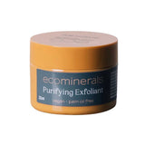 A small, round yellow container labeled Eco Minerals Purifying Exfoliator 32ml features walnut shell as a physical exfoliant. Its blue label notes vegan and palm oil free. Displayed against a white background.