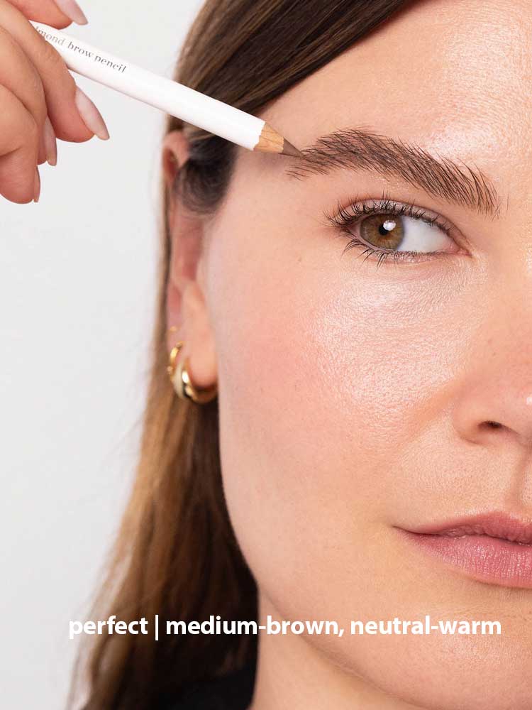 A person fills in their brows with the Ere Perez Almond Brow Pencil 1.1g for a natural, dewy look and well-groomed, medium-brown, neutral-warm eyebrows. Text at bottom: perfect | medium-brown, neutral-warm.