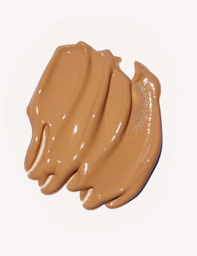 A close-up of Ere Perez Oat Milk Foundation 30ml, a creamy, medium-brown natural liquid foundation swatched in thick, smooth strokes on a white background.