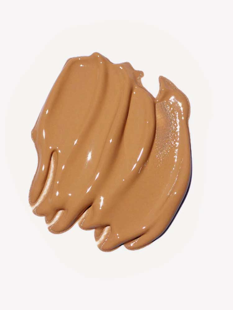 A close-up of Ere Perez Oat Milk Foundation 30ml, a creamy, medium-brown natural liquid foundation swatched in thick, smooth strokes on a white background.