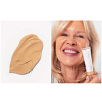 Swatch of beige Ere Perez Oat Milk Foundation 30ml on the left and a smiling older woman applying this natural medium coverage foundation in shade Chai (medium warm) to her cheek, holding the product tube. Text below: shade chai | medium warm | medium coverage.