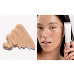 A swatch of Ere Perez Oat Milk Foundation 30ml in light-medium neutral shade “malt” appears on the left. On the right, a woman with radiant skin holds the natural liquid foundation tube by her face. Text below states: shade malt | light-medium neutral.