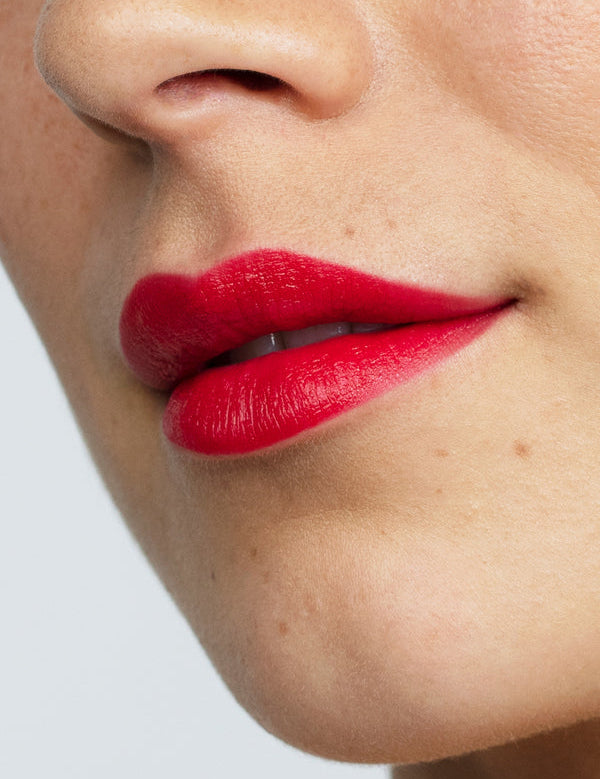 Model wearing Antipodes Moisture Boost Natural Lipstick in Forest Berry Red