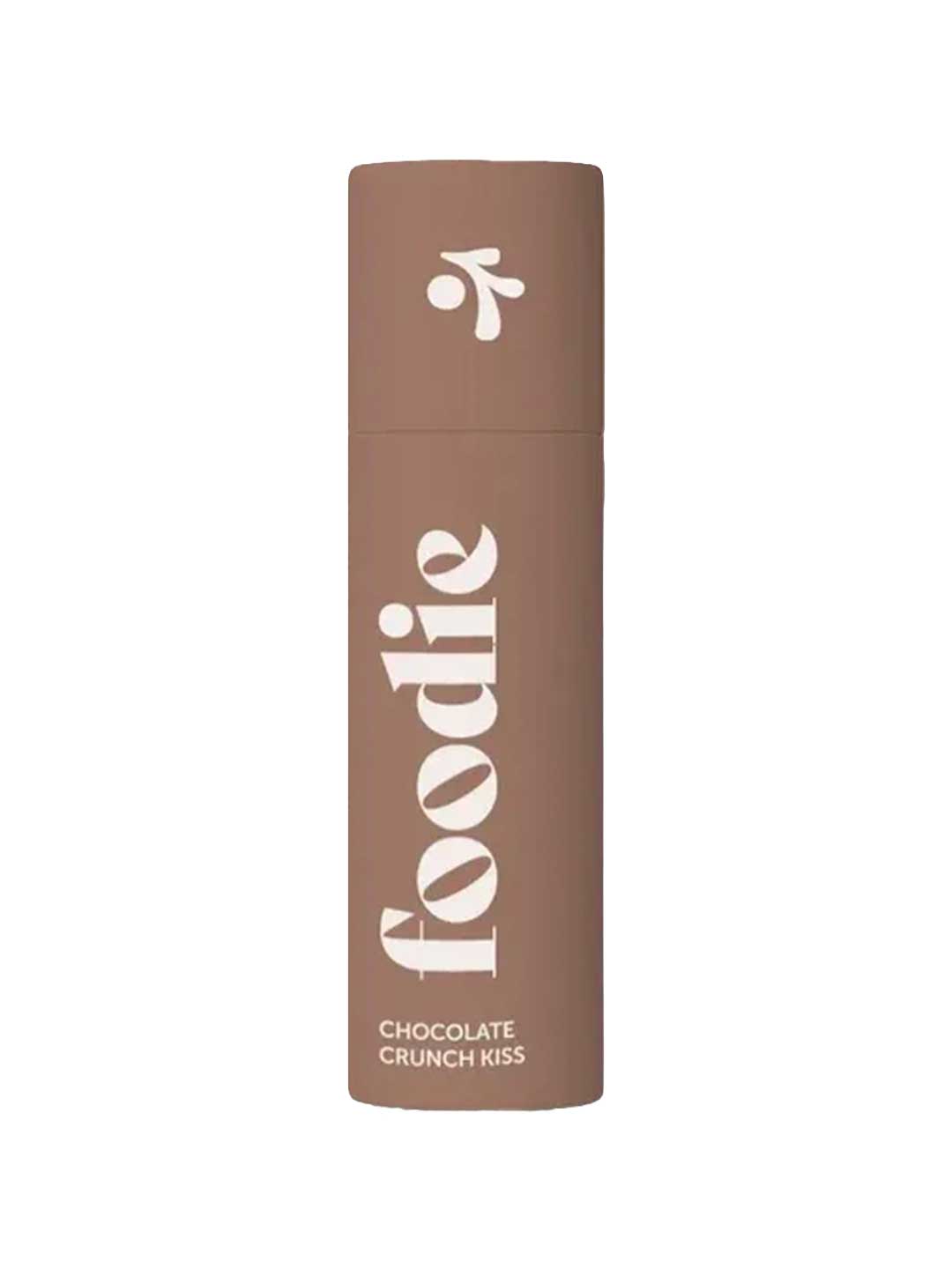 A brown cylindrical tube labeled "Foodie Chocolate Crunch Kiss Lip Balm 10g" stands upright against a white background—this chocolate lip balm features plastic-free packaging.