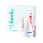 A light blue Foodie Foodie Juicy Skin Face Kit 4pc box displays three tween skincare essentials—a gentle cleanser in a white tube, a small purple bottle, and a smaller white tube—neatly arranged in front of the box.