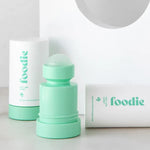 Mint-green Foodie Mint Lime Sorbet roll-on deodorant with its rounded roller ball exposed, standing beside white outer covers on a curved white display.