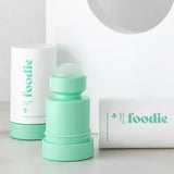 Mint-green Foodie Mint Lime Sorbet roll-on deodorant with its rounded roller ball exposed, standing beside white outer covers on a curved white display.