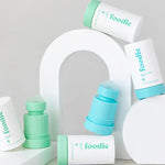 Foodie roll-on deodorants in mint green and turquoise, with rounded roller balls exposed, arranged among white outer covers and curved white display blocks.