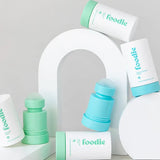 Foodie roll-on deodorants in mint green and turquoise, with rounded roller balls exposed, arranged among white outer covers and curved white display blocks.