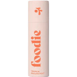 A light pink cylindrical bottle of Foodie Tropical Pavlova Pout Lip Balm 10g features large orange "foodie" lettering with "TROPICAL PAVLOVA POUT" below, both vertically aligned. The cap has an orange abstract design and is plastic-free.