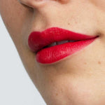 Close-up of a face with smooth skin and full lips wearing Antipodes Moisture Boost Natural Lipsticks 4g in vibrant Forest Berry Red, offers lasting colour and nourishment.