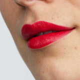Close-up of a face with smooth skin and full lips wearing Antipodes Moisture Boost Natural Lipsticks 4g in vibrant Forest Berry Red, offers lasting colour and nourishment.
