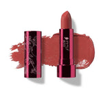 A tube of 100% Pure Fruit Pigmented® Pomegranate Oil Moisturising Lipstick 4.5g in Foxglove (berry pink mauve) sits uncapped beside a color smear. The shiny metallic case is embellished with floral designs. Brand: 100% Pure.
